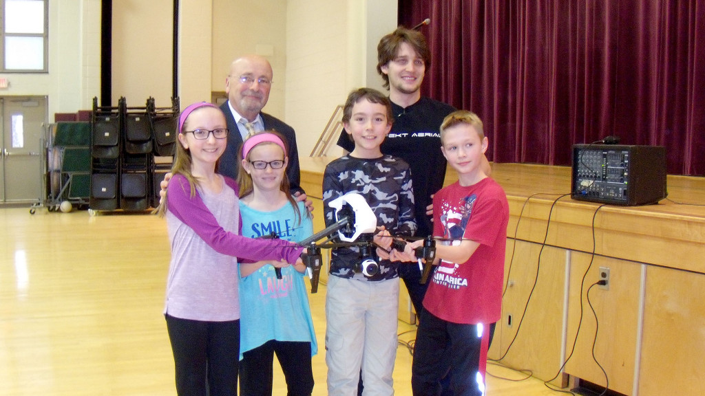 (above back l-r) Irene E. Feldkirchner (IEF) Elementary School Principal Armand Lamberti joins Connor Leszczuk, of Aspekt Aerial, Verona, during an IEF Elementary School assembly all about drones. (front, l-r) Madeline Mills, Paige Thomas, David Schreck and Michael Dumiec – are all IEF students who were up close to examine a drone. The students commented on how much they enjoyed the presentation and demonstration, citing how amazingly light drone materials can be, how uses of drones span from hobbyist to the commercial industry and how they can be used for search and rescue.