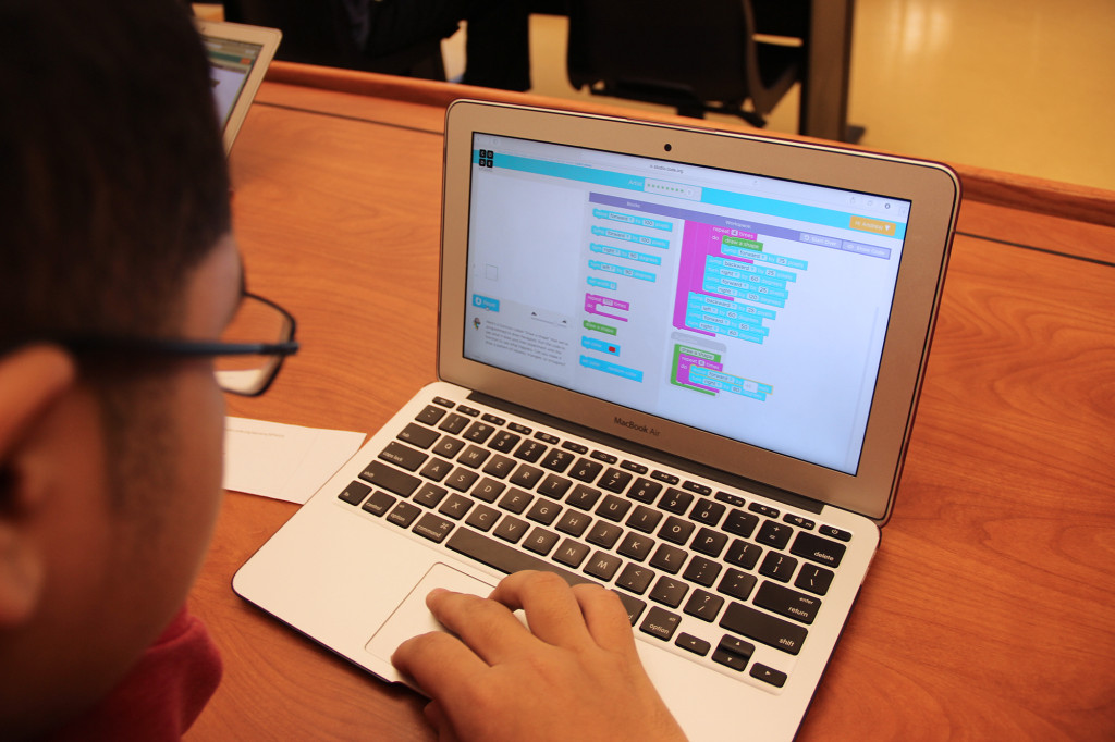 (above) Blue rectangular blocks are dragged into line on a screen as students code during the hour.